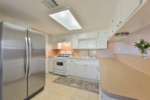 kitchen with visible vents, gas range gas stove, under cabinet range hood, freestanding refrigerator, and a sink