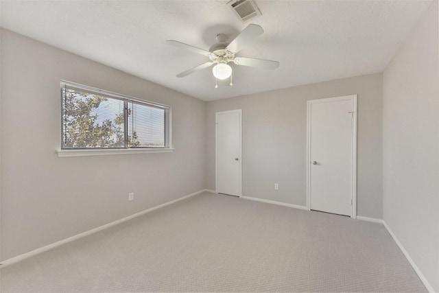 unfurnished bedroom with light carpet, visible vents, a ceiling fan, and baseboards