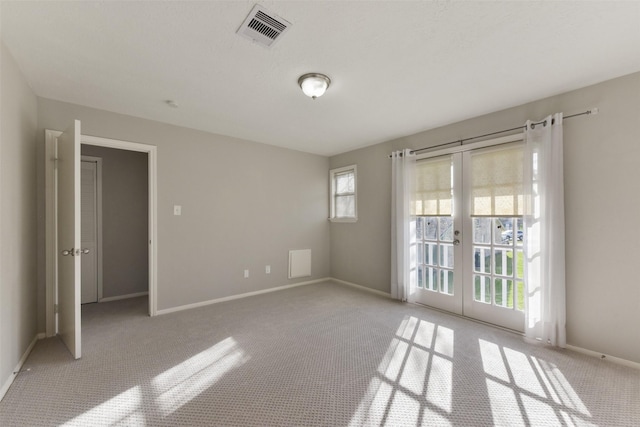 empty room with light carpet, french doors, visible vents, and baseboards