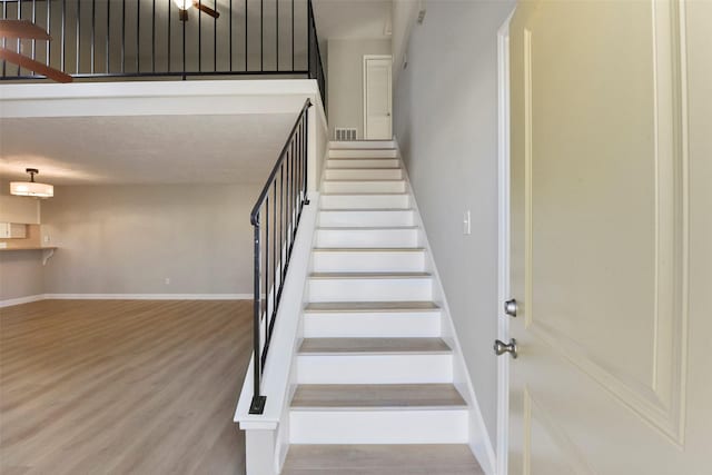 staircase with visible vents, wood finished floors, and baseboards