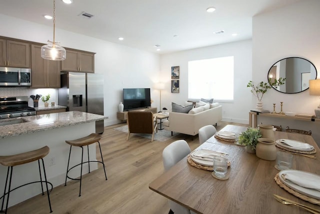 dining room featuring light wood-style floors, recessed lighting, visible vents, and baseboards