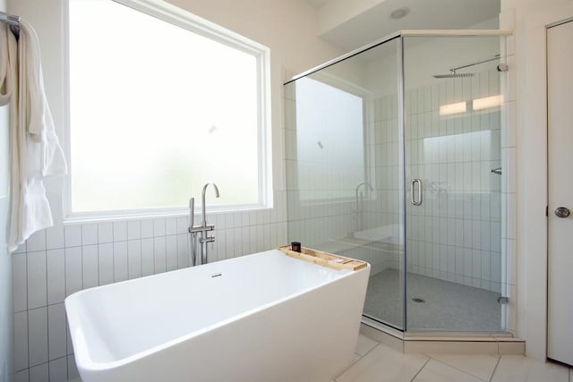 bathroom with tile patterned flooring, a freestanding bath, a shower stall, and tile walls