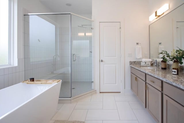 bathroom with a stall shower, a freestanding tub, vanity, and tile patterned floors