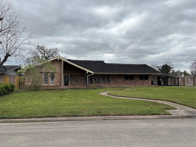 view of front facade featuring a front lawn, fence, and brick siding