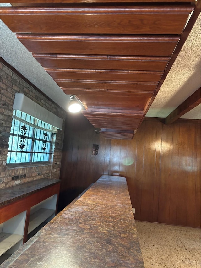 corridor featuring beamed ceiling and wood walls