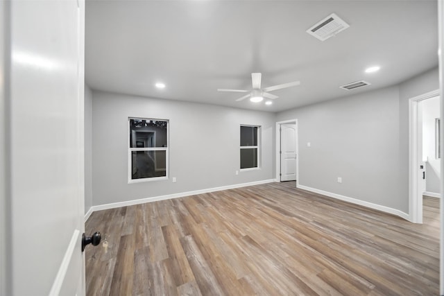 spare room with wood finished floors, visible vents, and baseboards