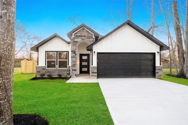 view of front of property with an attached garage, fence, stone siding, driveway, and a front yard