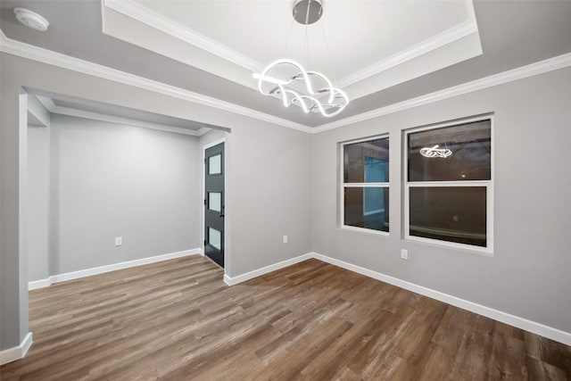 empty room with baseboards, a raised ceiling, wood finished floors, and a chandelier