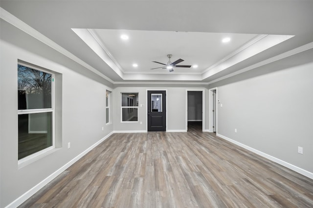 unfurnished living room featuring recessed lighting, a raised ceiling, ornamental molding, wood finished floors, and baseboards