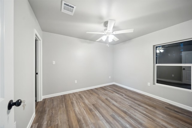 empty room with visible vents, ceiling fan, baseboards, and wood finished floors