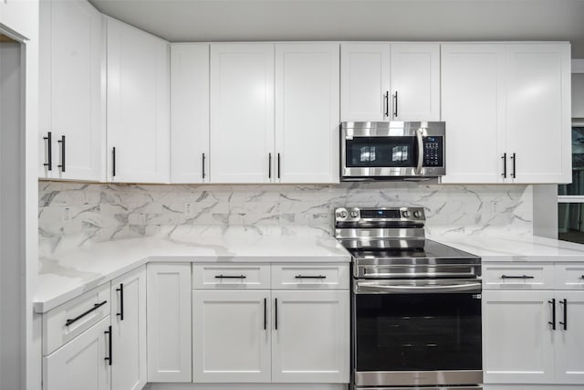 kitchen with stainless steel appliances, white cabinetry, and tasteful backsplash