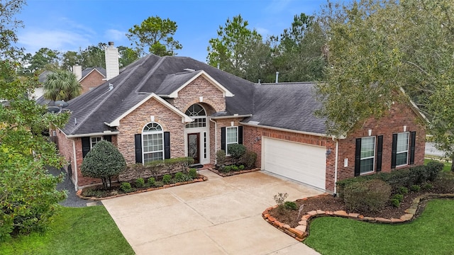 traditional home featuring brick siding, a shingled roof, concrete driveway, a garage, and stone siding