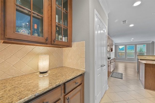 kitchen with brown cabinets, light tile patterned flooring, glass insert cabinets, and visible vents