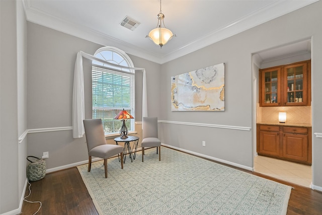 sitting room featuring ornamental molding, wood finished floors, visible vents, and baseboards