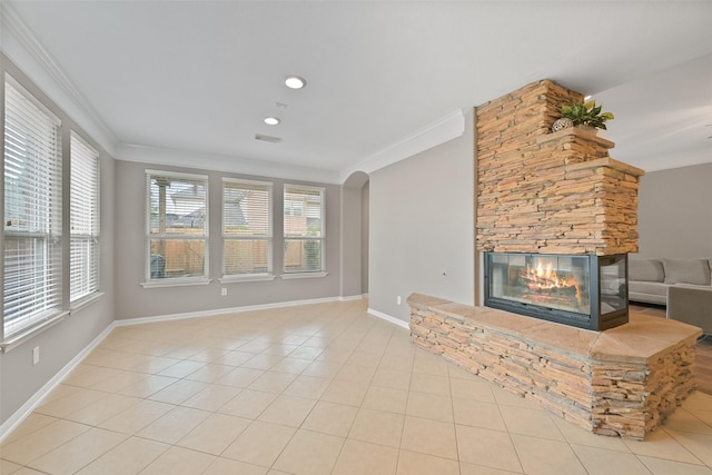 unfurnished living room with arched walkways, a stone fireplace, baseboards, ornamental molding, and tile patterned floors