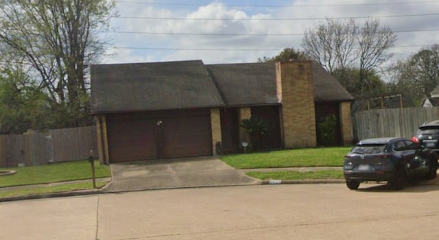 view of front of house featuring a garage, fence, a front lawn, and concrete driveway