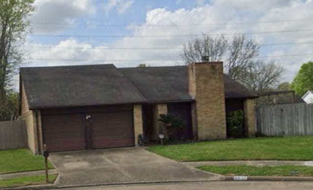 view of front of house with a garage, concrete driveway, fence, and a front lawn