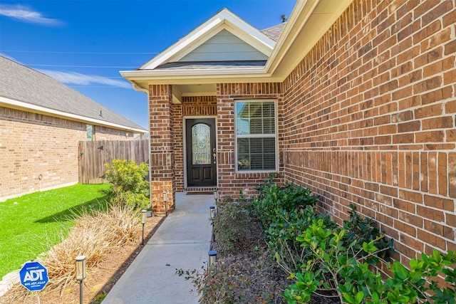 doorway to property with brick siding and fence