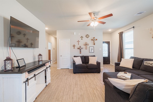 living room featuring light wood-style floors, visible vents, ceiling fan, and baseboards