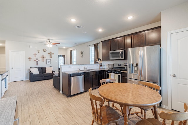 kitchen featuring stainless steel appliances, visible vents, a sink, dark brown cabinetry, and a peninsula