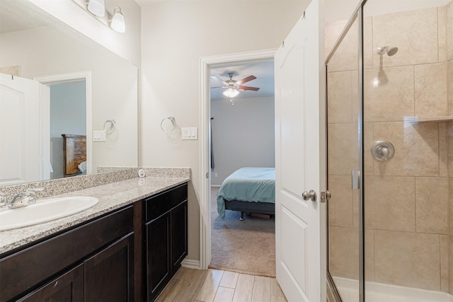 ensuite bathroom with ensuite bathroom, a ceiling fan, a stall shower, vanity, and wood finished floors