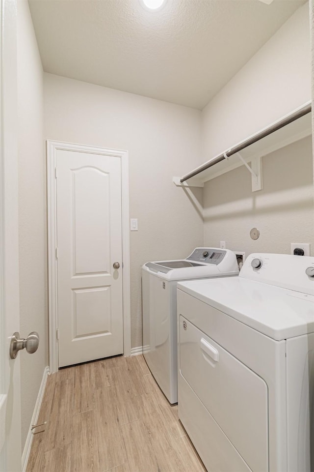 laundry room with baseboards, laundry area, separate washer and dryer, and light wood-style floors