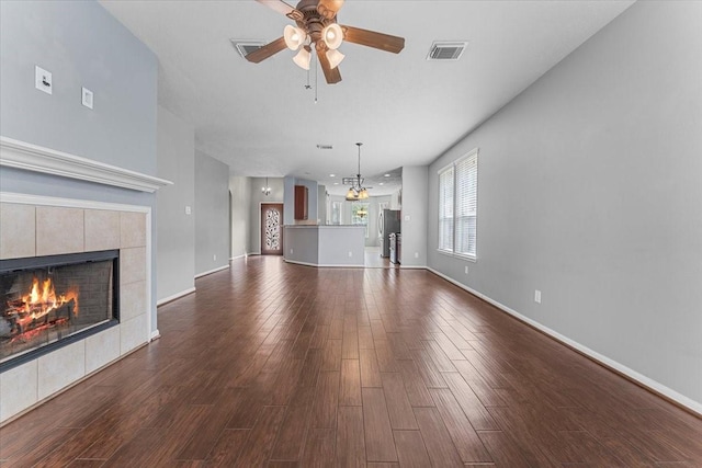 unfurnished living room with dark wood-style flooring, a fireplace, visible vents, ceiling fan, and baseboards