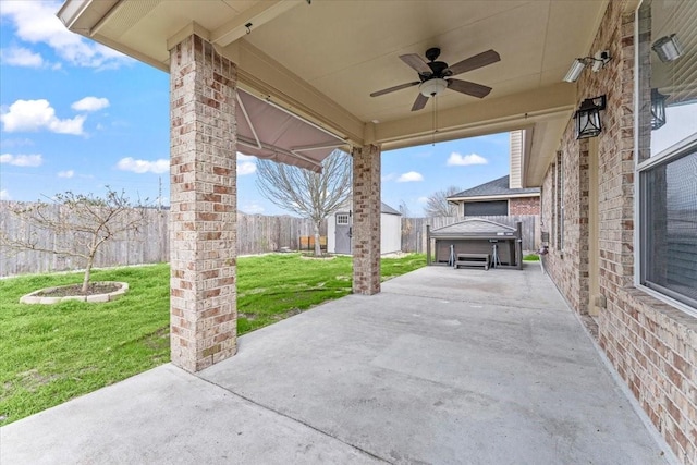 view of patio / terrace featuring a hot tub, a storage shed, a ceiling fan, a fenced backyard, and an outdoor structure