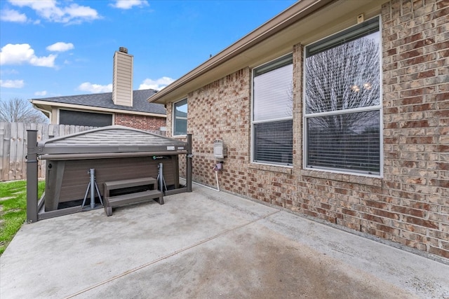 view of patio / terrace with fence and a hot tub