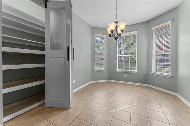 unfurnished dining area with a chandelier, baseboards, and light tile patterned floors