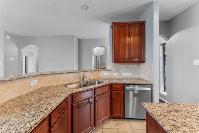 kitchen featuring tasteful backsplash, stainless steel dishwasher, light tile patterned flooring, a sink, and light stone countertops