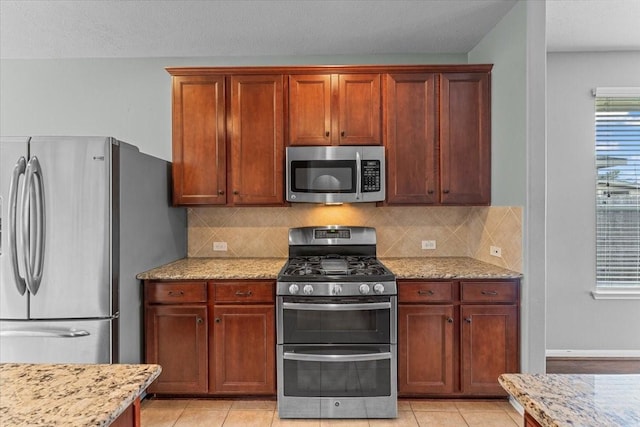 kitchen with appliances with stainless steel finishes, backsplash, and light stone countertops