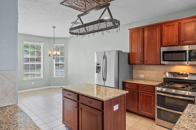 kitchen with light tile patterned floors, appliances with stainless steel finishes, hanging light fixtures, an inviting chandelier, and backsplash