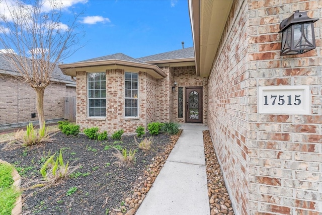 property entrance with brick siding and a shingled roof