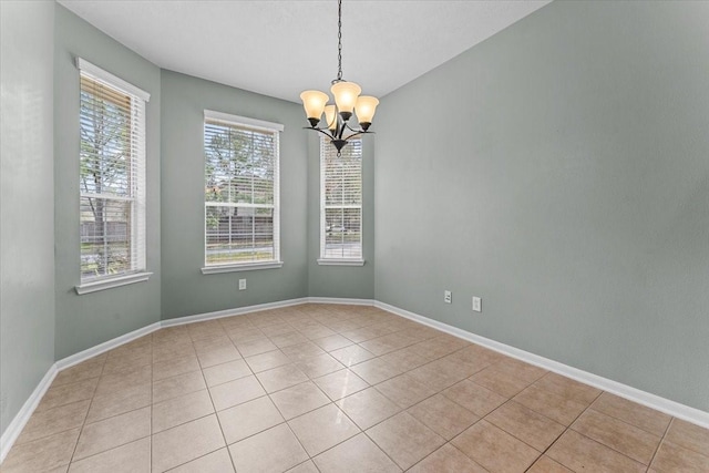 spare room featuring light tile patterned flooring, a notable chandelier, and baseboards