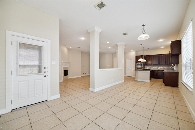 kitchen with visible vents, stainless steel microwave, ornate columns, and light tile patterned flooring