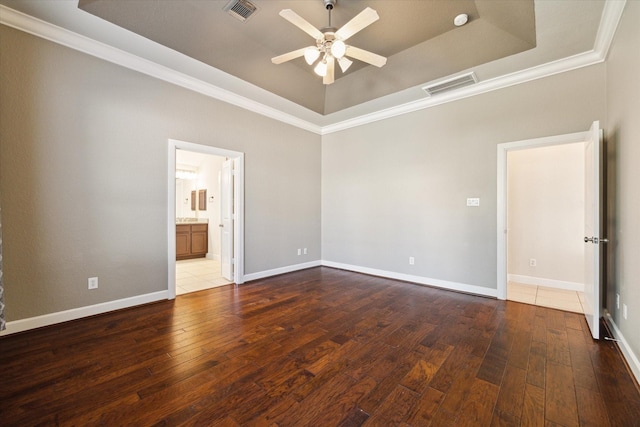 unfurnished room featuring visible vents, a tray ceiling, and hardwood / wood-style floors