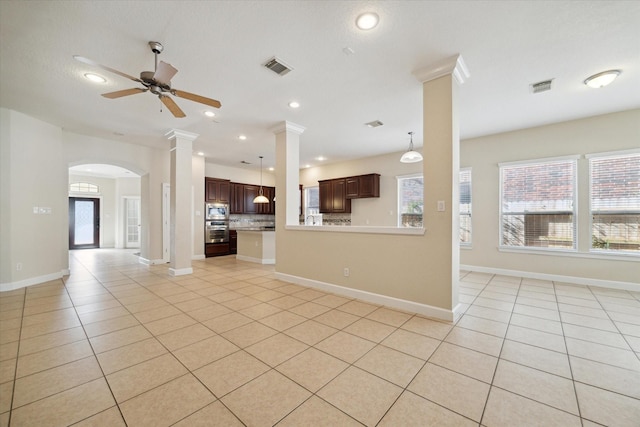 unfurnished living room featuring light tile patterned floors, a ceiling fan, visible vents, and ornate columns