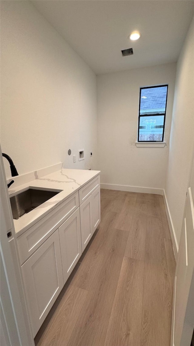 laundry area featuring hookup for a washing machine, light wood-style flooring, a sink, baseboards, and cabinet space