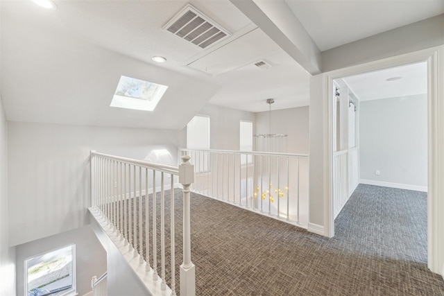 hallway featuring carpet, visible vents, lofted ceiling, and baseboards