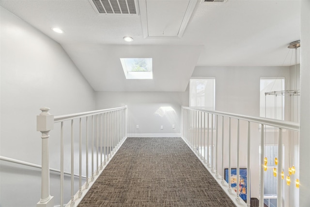 hallway with lofted ceiling, carpet flooring, visible vents, and baseboards