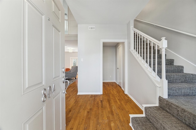 foyer featuring stairs, wood finished floors, visible vents, and baseboards