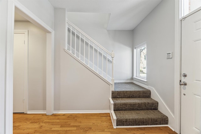 staircase featuring wood finished floors and baseboards