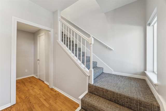 stairway featuring plenty of natural light, wood finished floors, and baseboards