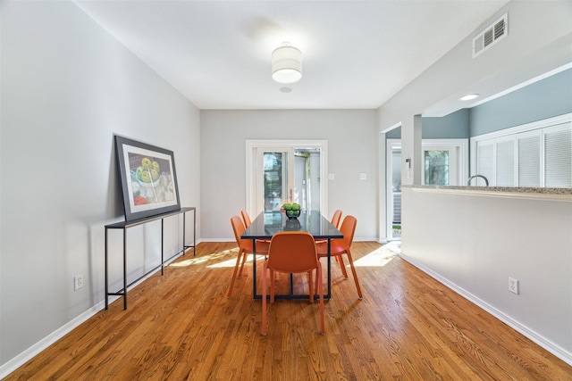 dining space featuring baseboards, visible vents, a wealth of natural light, and wood finished floors