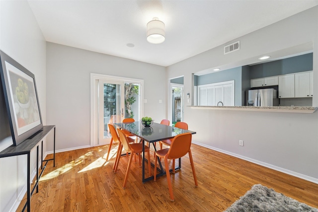 dining room with light wood finished floors, visible vents, and baseboards