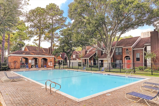 pool with a patio area, fence, and a residential view