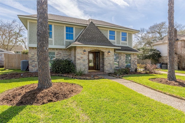 view of front of property featuring a shingled roof, stucco siding, fence, a front yard, and brick siding