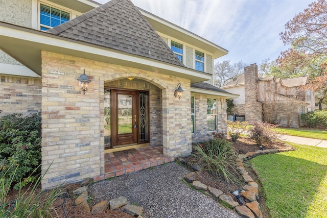 entrance to property featuring brick siding, mansard roof, and roof with shingles