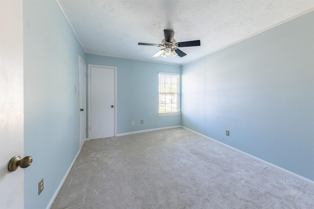 empty room featuring carpet, baseboards, ceiling fan, and crown molding